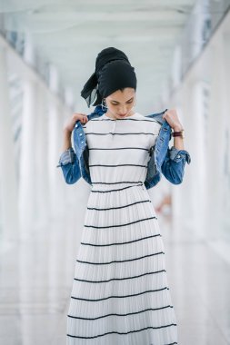 Genç, zarif ve çekici Malezyalı Müslüman kadın gün boyunca elbise ve kot ceket giyiyor..