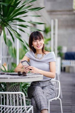 Çekici, kendine güvenen ve başarılı bir Çinli Asyalı kadının portresi. Akıllı telefonunu tutuyor. 