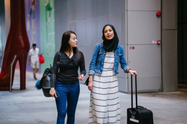 İki arkadaş, Orchard Road, Singapur, Asya 'da aydınlık bir yaz gününde mutlu bir şekilde yürüyüp konuşurlar. Biri Müslüman Malezyalı, diğeri Çinli bir kadın.. 