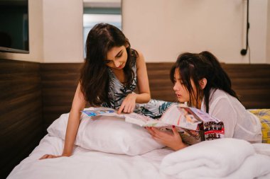 İki genç Asyalı arkadaş bir pansiyonda bir yatakta oturuyor. İkisi de Asyalı ve birlikte seyahat ediyorlar. Biri Hintli, diğeri Çinli. İkisi de gündelik giysiler içinde ve odalarında dinleniyorlar..