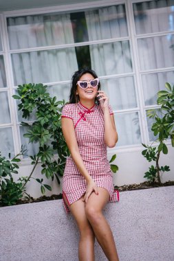 Bir şık, güzel ve genç genç Asyalı kız onun smartphone üzerinde konuşuyor. Geleneksel Çince elbise giyiyor 