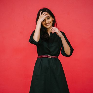 Stüdyo bir güzel, Genç ve çekici Hint Asyalı kadın kırmızı studio çerçevede bir portresi. O zarif bir basit yeşil elbise ve kırmızı kuşak giymiş ve gülüyor.