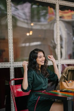 Genç Hintli Asyalı kadın o onun Smartphone-e doğru onun kulaklık streaming müzik hoşlanır