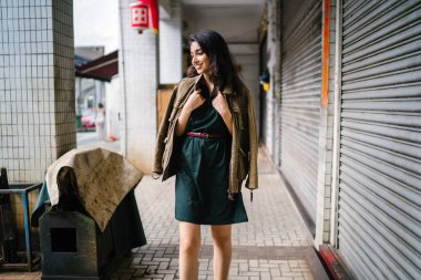 Hint Asyalı kadın Genç, uzun boylu, ince ve zarif bir portre için poz veriyor. O rahat ve şık rahat giysiler giyiyor ve bir adamın ceketi omuzları üzerinde bol dökümlü vardır. 