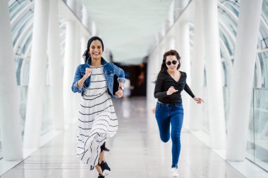 İki farklı arkadaş, iyi aydınlatılmış beyaz fütüristik bir üstgeçit köprüsünden kameraya doğru koşuyorlar. Biri Müslüman bir Orta Doğulu kadın, diğeri de Çinli..