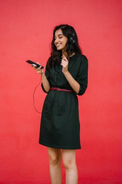 Bir güzel, Genç ve çekici Hint Asyalı kadın bir yeşil elbise ve kırmızı bir arka plan kırmızı kemer Studio portresi