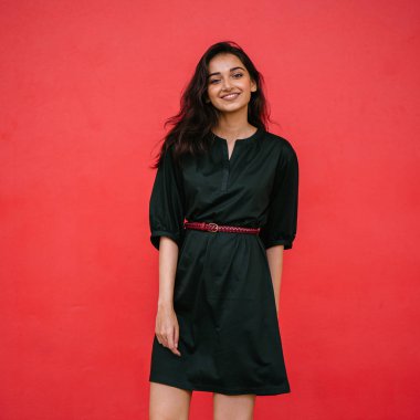 Stüdyo bir güzel, Genç ve çekici Hint Asyalı kadın kırmızı studio çerçevede bir portresi. O zarif bir basit yeşil elbise ve kırmızı kuşak giymiş ve gülüyor.