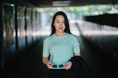 Gündüz vakti genç, seksi ve çekici bir Asyalı kadının portresi. O nane yeşili bir kazak giyiyor.