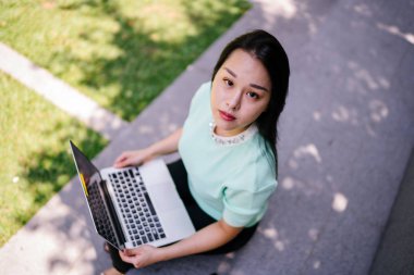 Genç ve çekici bir Asyalı kadın öğrenci oturur ve gün boyunca bir üniversite kampüsünde onu dizüstü bilgisayar üzerinde çalışır. O, o çalışırken gelişigüzel giyinmiş. 