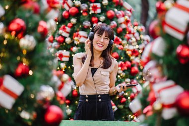 Gün boyunca birkaç süslü Noel ağaçları arasında duran zarif ve çekici bir orta yaşlı kadın portresi