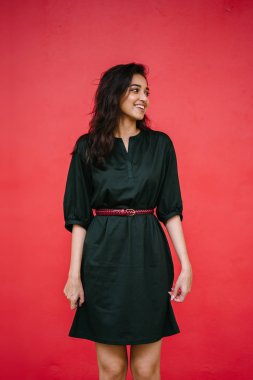 Stüdyo bir güzel, Genç ve çekici Hint Asyalı kadın kırmızı studio çerçevede bir portresi. O zarif bir basit yeşil elbise ve kırmızı kuşak giymiş ve gülüyor.