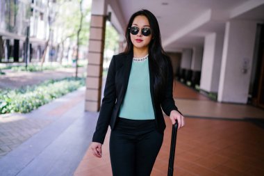 Genç bir Asyalı kadın bavulunu çekiyor. O çekici, zarif ve şık giyinmiş