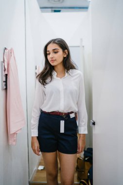 Trying dışarı giyim moda mağaza montaj odasında bir genç, uzun boylu, güzel ve zarif Hint Asyalı kadın portresi.