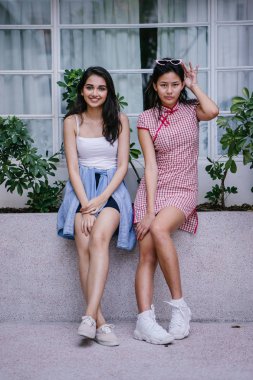 farklı etnik yapı birlikte dışarı asılı iki genç kadın arkadaşlar. Bir Çinli bir kadını bir cheongsam ve diğer bir Hint kadının modaya uygun bir kıyafet olduğunu