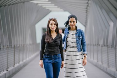 Gündüz vakti köprüde farklı etnik kökenlere sahip iki arkadaş. Biri Malezyalı Müslüman bir kadın, diğeri de Çinli bir Asyalı. İkisi de genç, enerjik ve çekici..