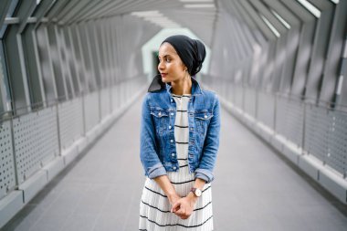 Gün boyunca güzel bir köprüde tek başına duran uzun boylu, genç, zarif ve çekici Malezyalı Müslüman bir kadının portresi..