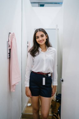 Trying dışarı giyim moda mağaza montaj odasında bir genç, uzun boylu, güzel ve zarif Hint Asyalı kadın portresi.