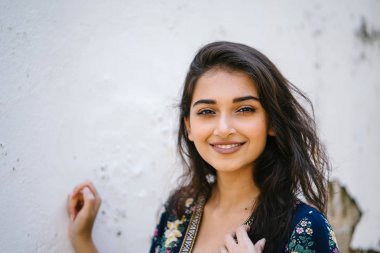 bir sokakta yıpranmış bir duvara portre genç bir uzun boylu, zarif ve güzel Hint Asyalı kadın akan içinde elbise 