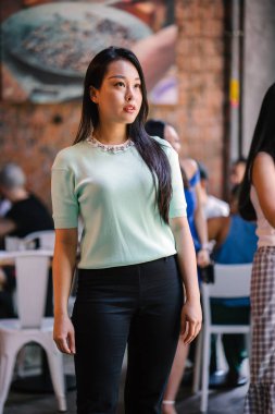 Gündüz vakti genç, seksi ve çekici bir Asyalı kadının portresi. O nane yeşili bir kazak giyiyor.