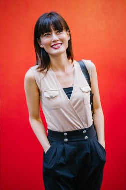 Bir çalışma hanım o pozlar ve onun baş shot kırmızı bir arka plan için gülümsüyor olarak stüdyo portresi