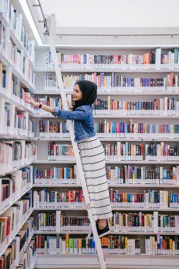 Genç, uzun, zayıf, çekici ve güzel Malezyalı Müslüman kadın kütüphanede