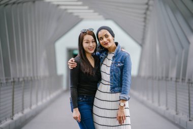 Gündüz vakti köprüde farklı etnik kökenlere sahip iki arkadaş. Biri Malezyalı Müslüman bir kadın, diğeri de Çinli bir Asyalı. İkisi de genç, enerjik ve çekici..