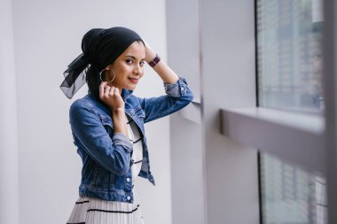 Genç, zarif ve çekici Malezyalı Müslüman kadın gün boyunca elbise ve kot ceket giyiyor..