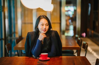 Bir açık havada açık havada oturan ve kırmızı bir çay seti çay sıcak bir fincan zevk genç, çekici, zarif ve güzel Asyalı kadın Portresi. 