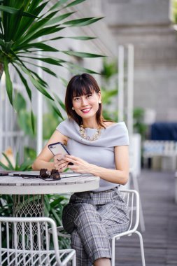 Çekici, kendine güvenen ve başarılı bir Çinli Asyalı kadının portresi. Akıllı telefonunu tutuyor. 