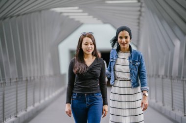 Gündüz vakti köprüde farklı etnik kökenlere sahip iki arkadaş. Biri Malezyalı Müslüman bir kadın, diğeri de Çinli bir Asyalı. İkisi de genç, enerjik ve çekici..