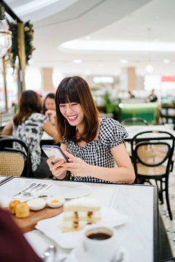 Bir Çinli Asyalı bayan bir restoranda iyi bir arkadaş ile yüksek çay sahiptir. O güzel, zarif ve o bir hafta sonu kek ve çay üzerinde arkadaşı ile animatedly konuşuyor gibi gülümsüyor. 