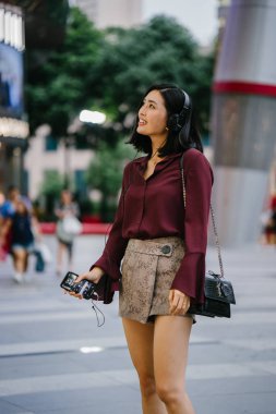 şık bir bluz ve şort olarak o yürür onu kulaklık ile şehirde bir sokakta dans güzel Koreli kadın