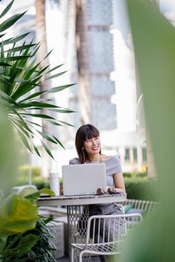 Modern dizüstü bilgisayar kullanarak çekici, kendine güvenen ve başarılı bir Çinli Asyalı kadının portresi