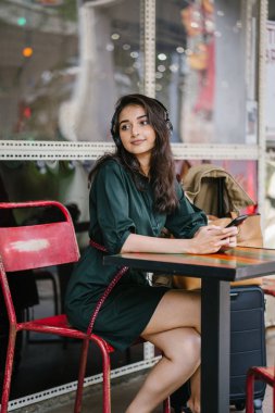 Genç Hintli Asyalı kadın o onun Smartphone-e doğru onun kulaklık streaming müzik hoşlanır