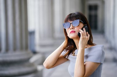 Çekici, kendine güvenen ve başarılı bir Çinli Asyalı kadının portresi. Akıllı telefonuyla konuşuyor. 