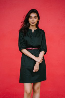 Stüdyo bir güzel, Genç ve çekici Hint Asyalı kadın kırmızı studio çerçevede bir portresi. O zarif bir basit yeşil elbise ve kırmızı kuşak giymiş ve gülüyor.