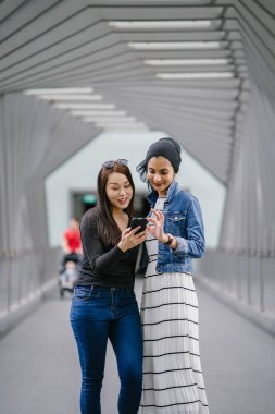 Gündüz vakti köprüde farklı etnik kökenlere sahip iki arkadaş. Biri Malezyalı Müslüman bir kadın, diğeri de Çinli bir Asyalı. İkisi de genç, enerjik ve çekici..