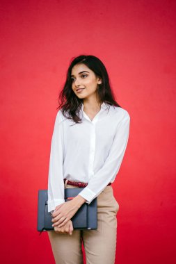 O onun laptop ve defter tutar olarak beyaz bir gömlek ve kahverengi pantolon giyen genç Hintli Asya öğrenci kız portresi.