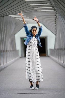 Güzel bir köprünün geçidinde duran uzun boylu, zarif ve ince bir Orta Doğulu kadının portresi (geometrik desenler)).