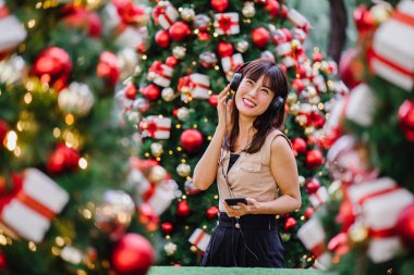 Gün boyunca birkaç süslü Noel ağaçları arasında duran zarif ve çekici bir orta yaşlı kadın portresi