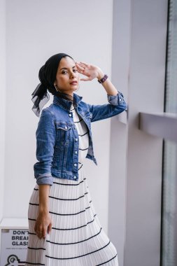 Genç, zarif ve çekici Malezyalı Müslüman kadın gün boyunca elbise ve kot ceket giyiyor..