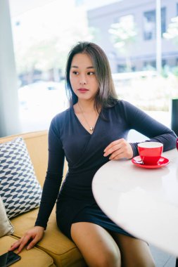 Bir açık havada açık havada oturan ve kırmızı bir çay seti çay sıcak bir fincan zevk genç, çekici, zarif ve güzel Asyalı kadın Portresi. 