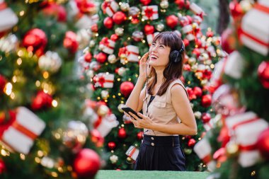 Gün boyunca birkaç süslü Noel ağaçları arasında duran zarif ve çekici bir orta yaşlı kadın portresi