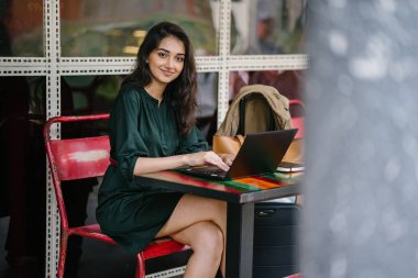 genç üniversite öğrencisi (Hint Asyalı kadın) eğitim ve gün boyunca dizüstü bilgisayar bir masa başında çalışma