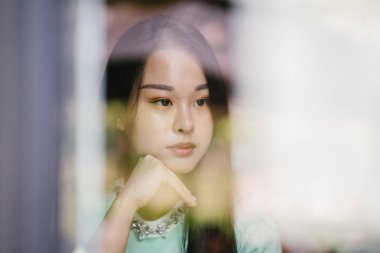 Gündüz vakti genç, seksi ve çekici bir Asyalı kadının portresi. O nane yeşili bir kazak giyiyor.