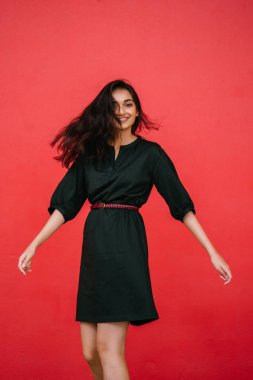 Stüdyo bir güzel, Genç ve çekici Hint Asyalı kadın kırmızı studio çerçevede bir portresi. O zarif bir basit yeşil elbise ve kırmızı kuşak giymiş ve gülüyor.