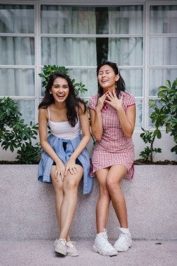 farklı etnik yapı birlikte dışarı asılı iki genç kadın arkadaşlar. Bir Çinli bir kadını bir cheongsam ve diğer bir Hint kadının modaya uygun bir kıyafet olduğunu