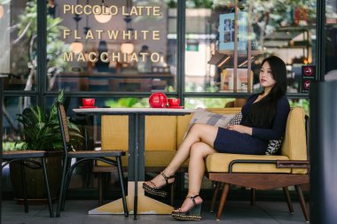 Bir açık havada açık havada oturan ve kırmızı bir çay seti çay sıcak bir fincan zevk genç, çekici, zarif ve güzel Asyalı kadın Portresi. 