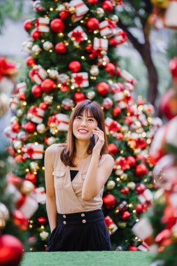 güzel orta yaşlı kadın mutlu onun smartphone üzerinde konuşuyor ve aynı derecede o durgunluk ortasında güzel gülümseyen gün boyunca Noel ağaçları dekore edilmiş olan