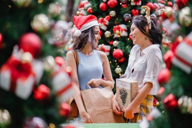 İki genç Asyalı kızlar exchange bir başka gün boyunca şehrin bir sokakta bir şekilde dekore edilmiş bir Noel ağacı altında sunuyor. Hint, diğer Çinli biri